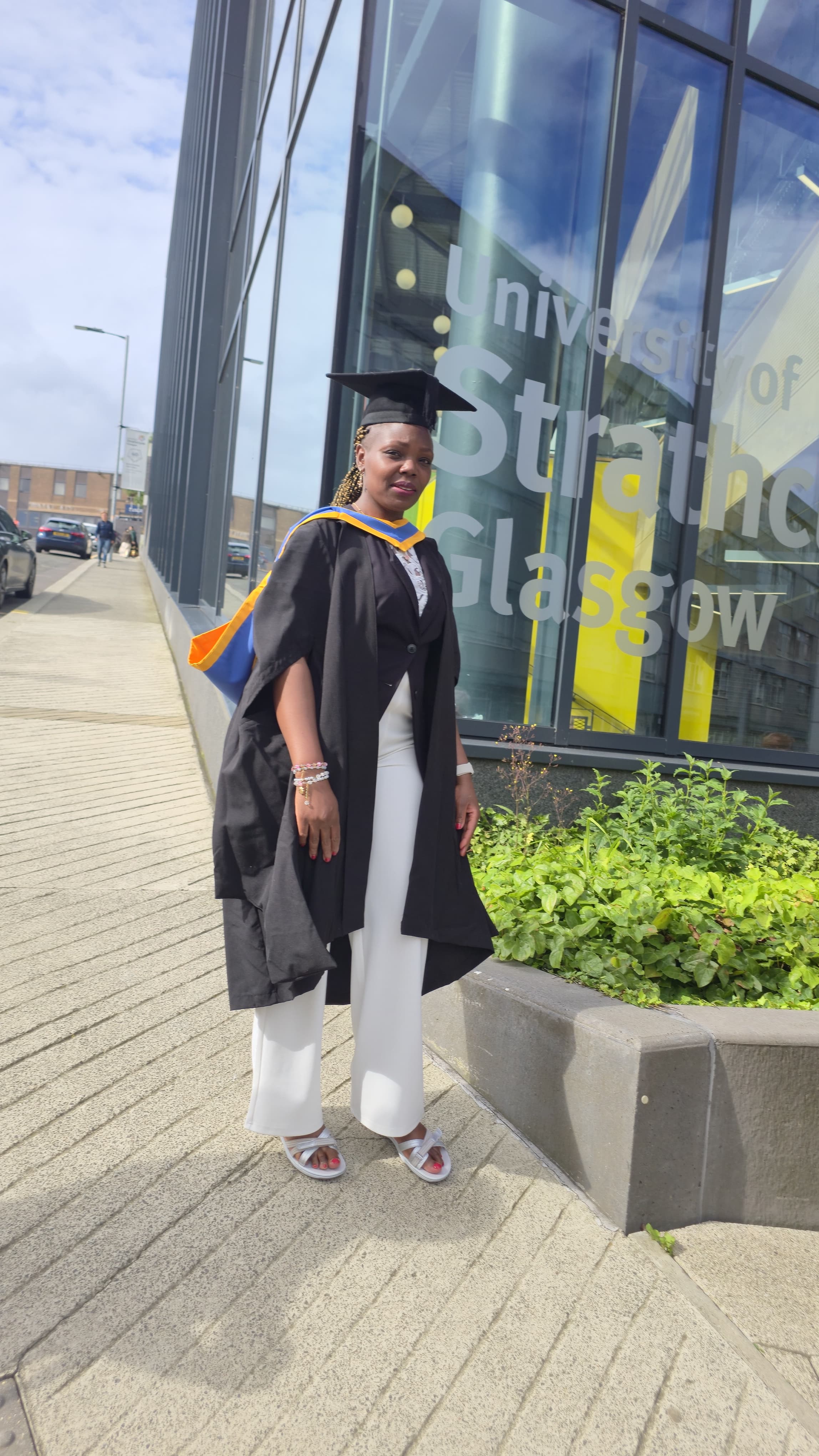 Catherine Cherotich posing outside the University of Strathclyde campus in her graduation gown