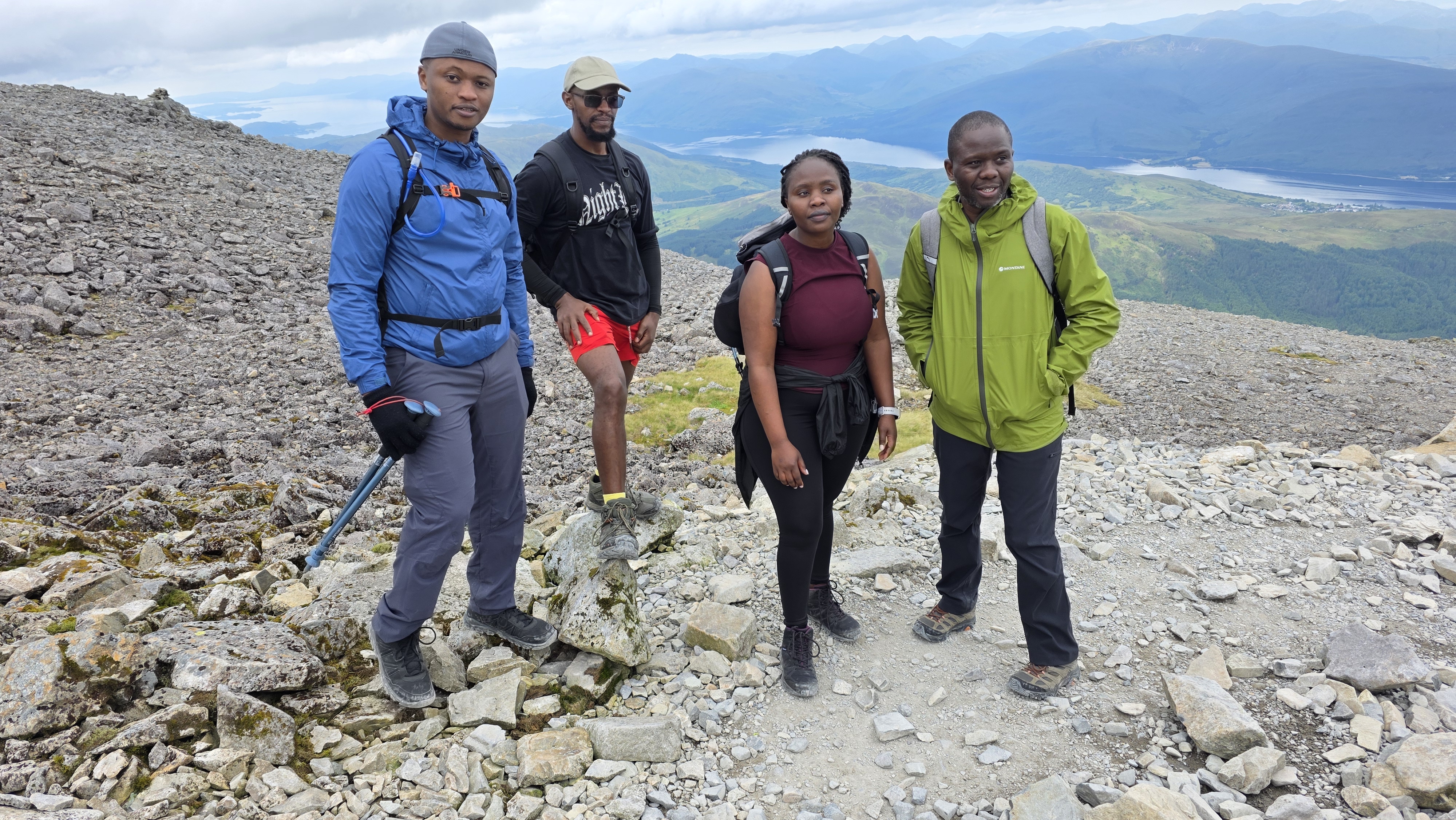 Group of four hikers resting with a spectacular loch view in the background