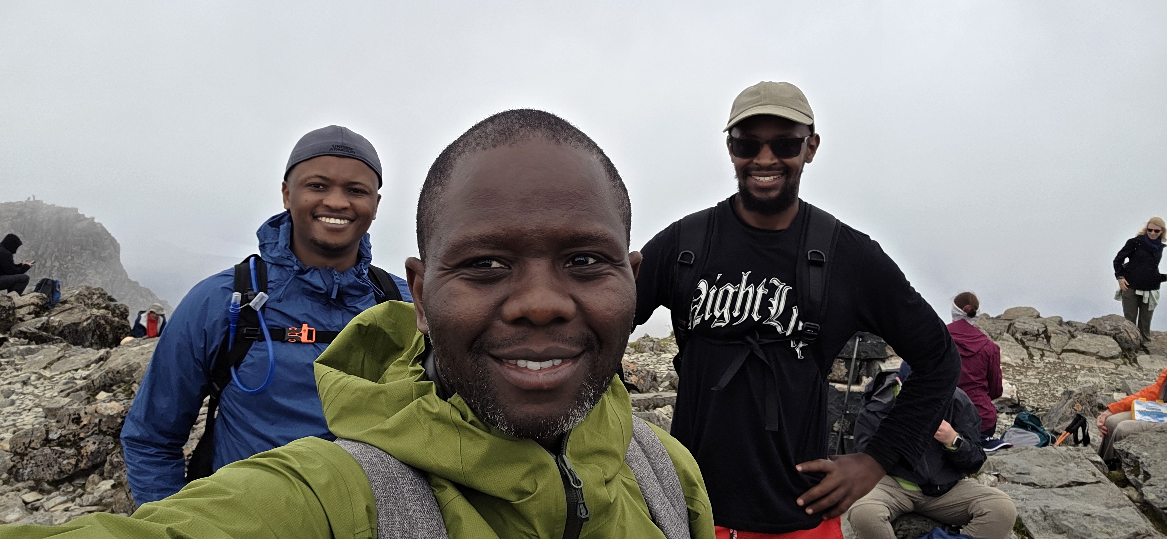 Summit selfie with beaming smiles and misty skies all around